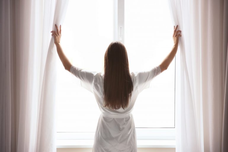 Woman Opening Curtain and looking outside