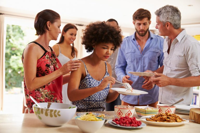 Friends serving themselves food and talking at dinner party